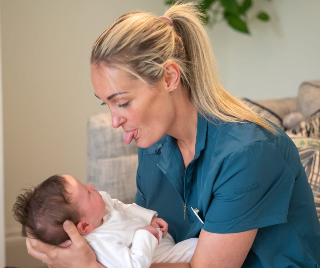 Midwife sticking tongue out at baby follow-up tongue tie