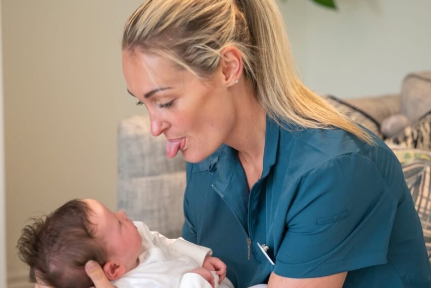 Midwife sticking tongue out at baby follow-up tongue tie